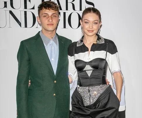 A woman in a stylish black and white outfit stands beside a man in a green suit at a fashion event.