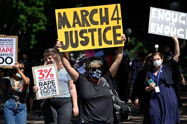 Protesters hold signs, including "March 4 Justice," at a rally advocating against violence and injustice.