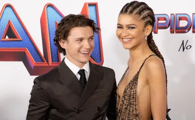 Two actors smiling at the red carpet of a 'Spider-Man: No Way Home' event.