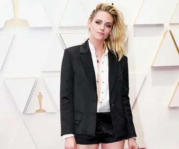 Kristen Stewart at the 2022 Oscars in a black blazer, white shirt, and shorts on the red carpet.