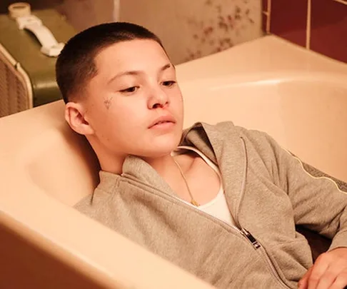 Young person in a gray hoodie reclines in a bathtub, looking contemplative. Scene from Euphoria Season 2 featuring Ashtray.