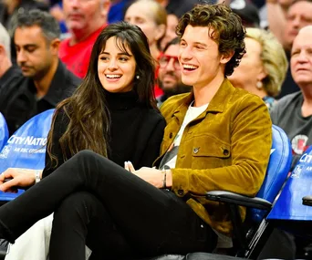 A couple smiling while sitting at a sports event, surrounded by other attendees.