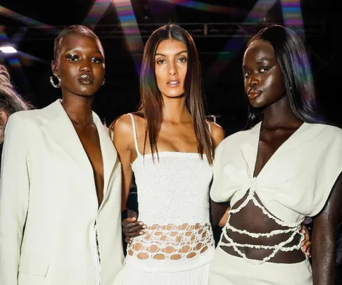 Three models in stylish white outfits pose at Afterpay Australian Fashion Week 2022.