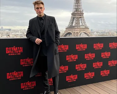 Man in black suit at The Batman event in Paris, Eiffel Tower in background.