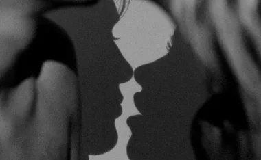 Shadow of two faces about to kiss against a wall.