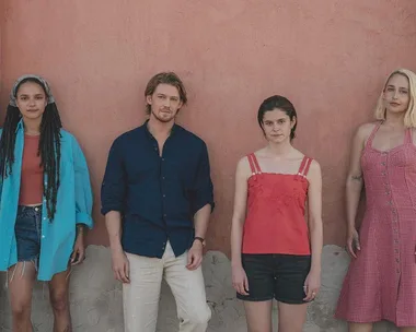 The cast of "Conversations with Friends" stands against a peach wall, dressed casually in summery clothes.