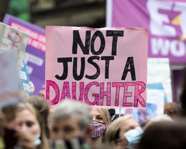 Protesters hold signs, including one reading "Not Just a Daughter," advocating against sexual assault in Australia.