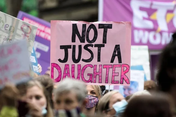 Protesters hold signs, including one reading "Not Just a Daughter," advocating against sexual assault in Australia.