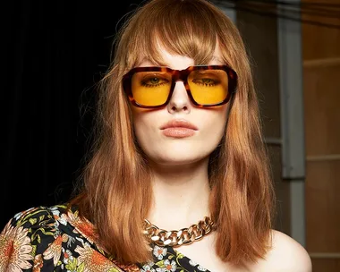 A model with a 70s wolf cut, wearing large brown sunglasses and a floral top, at Australian Fashion Week 2022.