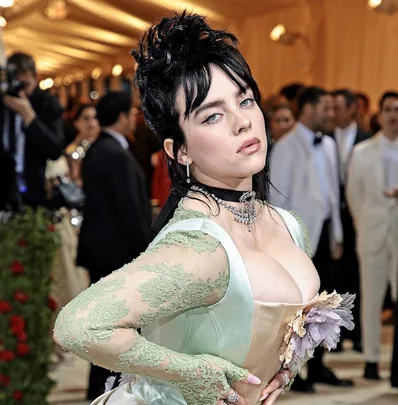 Billie Eilish at the 2022 Met Gala in a pale green corset gown with floral details and black choker necklace.