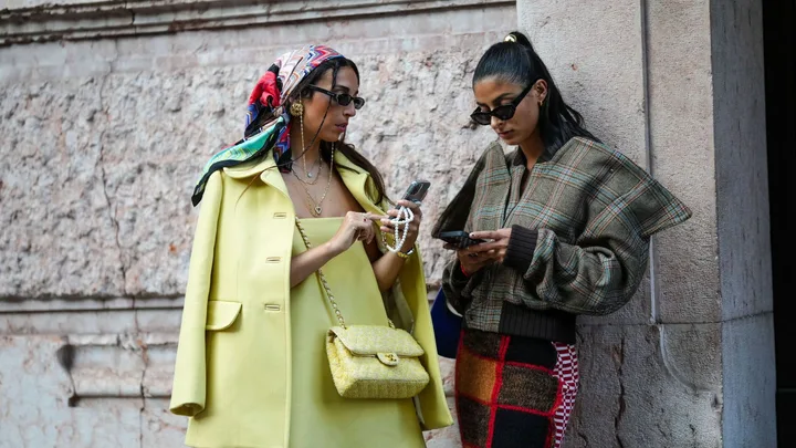 two girls looking at their phones on the street