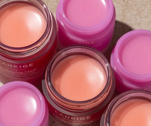 Colorful jars of Laneige lip sleeping masks arranged on a textured surface.