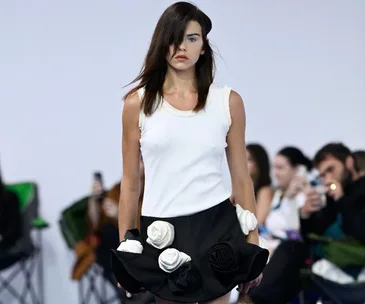 Model in a white top and floral black skirt walking runway at Australian Fashion Week 2022.