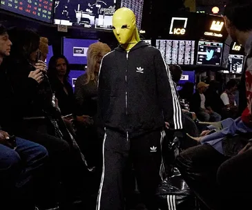 Model in yellow mask and Adidas tracksuit walks Balenciaga Resort 2023 runway at NYSE.