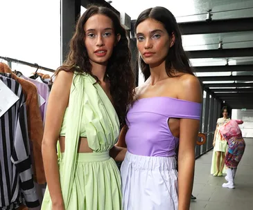 Two models backstage in pastel green and purple outfits at Australian Fashion Week 2022.