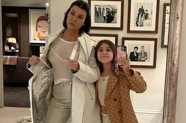 Mother and daughter pose in a mirror selfie, with framed pictures in the background.