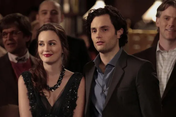 Blair and Dan standing together at a social event, surrounded by others, from "Gossip Girl".