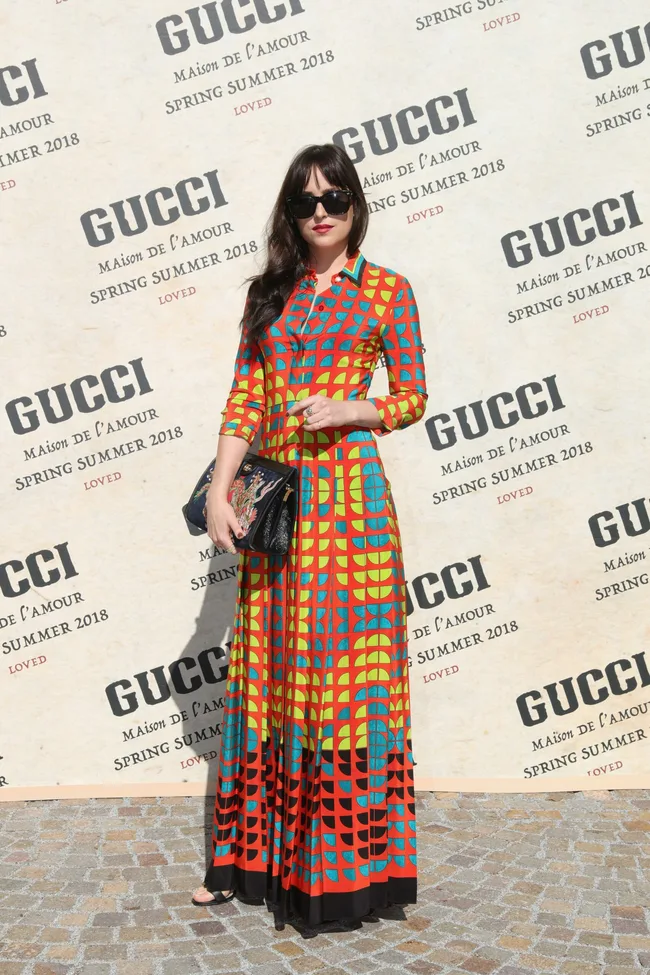 A woman in a colorful patterned dress and sunglasses at the Gucci Spring Summer 2018 fashion event.