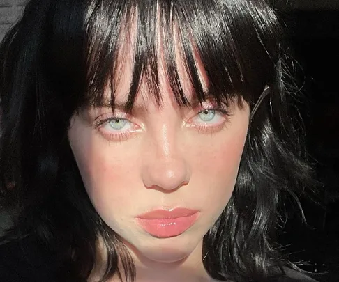 A woman with black hair and blue eyes, facing the camera with sunlight highlighting her face.