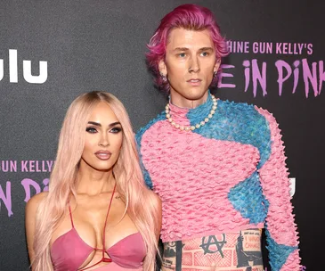 Two individuals posed at an event for "Machine Gun Kelly's Life in Pink" premiere.