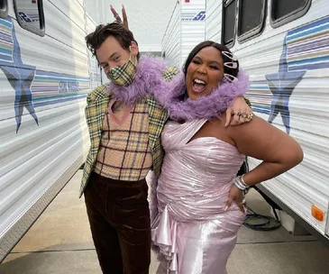 A man and a woman are posing playfully between trailers, the woman is laughing and the man is giving bunny ears.