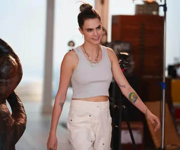 Person in a cropped tank top and pants smiles on set, linked to "Only Murders in the Building."