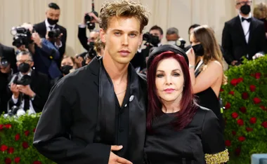 Austin Butler and Priscilla Presley at a formal event, surrounded by photographers.