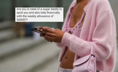 Woman in pink cardigan using phone with text offering financial help from a "sugar daddy."