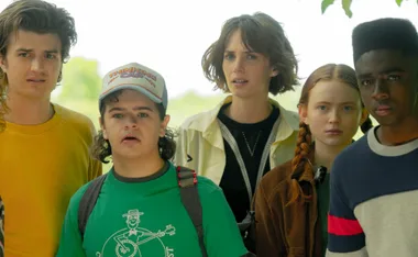 The "Stranger Things" characters are standing together outside, looking concerned.