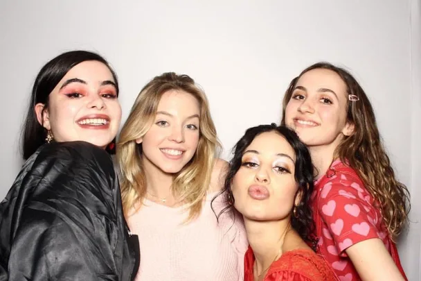 Four women smiling and posing together in a well-lit setting.