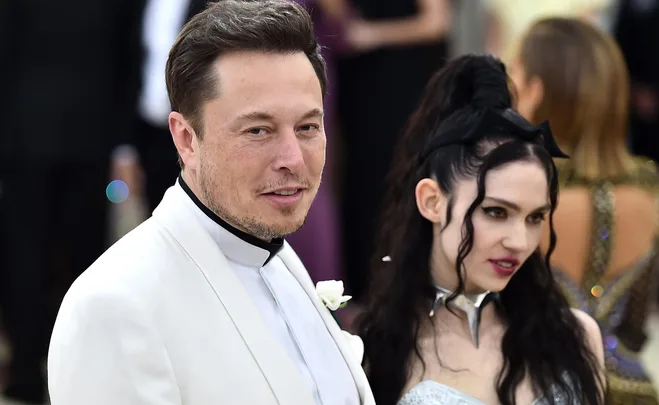 A man in a white suit and a woman with dark hair wearing a silver outfit at a formal event.