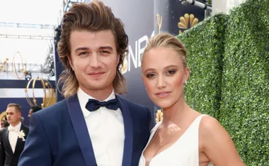 A couple poses together on a red carpet at an awards event, both dressed in formal attire.