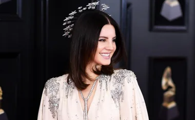 Smiling woman in a sparkling gown with star headpiece at an award event.