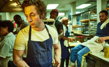 A busy restaurant kitchen with chefs focused on their tasks, wearing aprons.