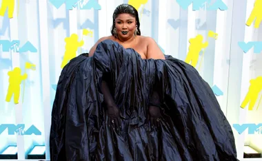 Singer in a voluminous black dress on the MTV VMAs red carpet with bold makeup and statement hoop earrings.