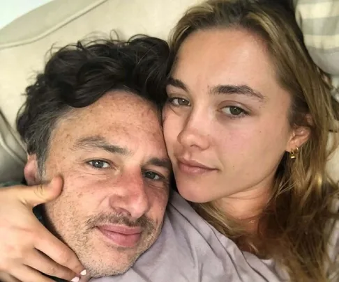 A couple lying together, facing the camera with a calm expression, close up shot on a couch.