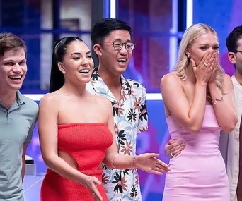 Four contestants from "Beauty and the Geek 2022" react with excitement and surprise on stage.