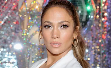 A close-up of a person with hoop earrings and a sparkling background.