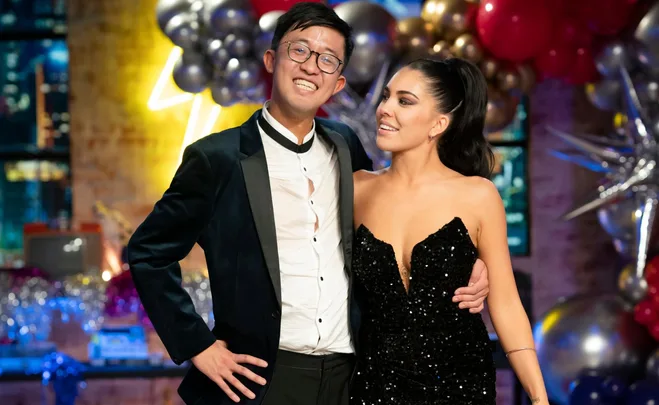 Man and woman smiling at an event, surrounded by balloons and festive decorations.