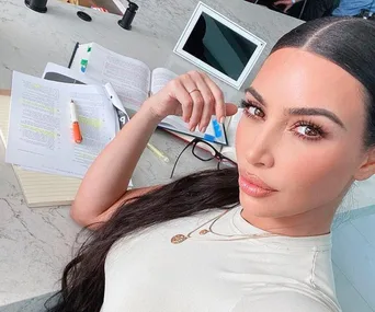 Person taking a selfie at a table with legal books, notebooks, and a tablet.