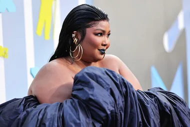 Lizzo at the 2022 VMAs in a dramatic black gown with sleek hair and bold makeup.