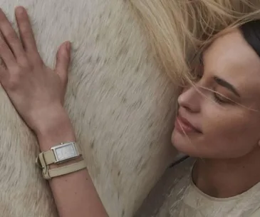 Woman wearing Longines watch, gently embracing a horse, looking serene.