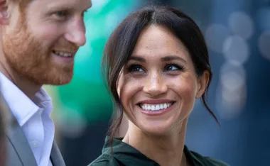 Smiling couple close-up, woman with dark hair, man with red beard, engaged in conversation outdoors.