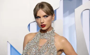 Singer wearing a jeweled dress with bold red lipstick, posing against a light background.