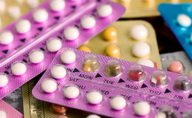 Blister packs of contraceptive pills in various colors and designs, arranged closely together.