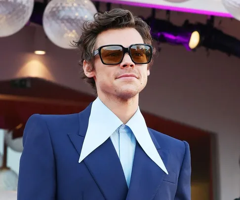 Man in a blue suit with oversized collars and sunglasses at the "Don't Worry Darling" premiere.