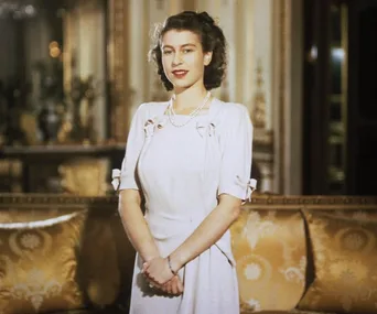 A young Queen Elizabeth II in a white dress, standing in a richly decorated room with gold cushions.