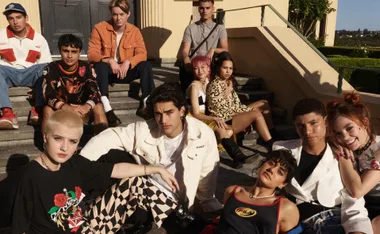 Group of diverse teenagers sitting and standing on outdoor steps, dressed in trendy, youthful fashion.