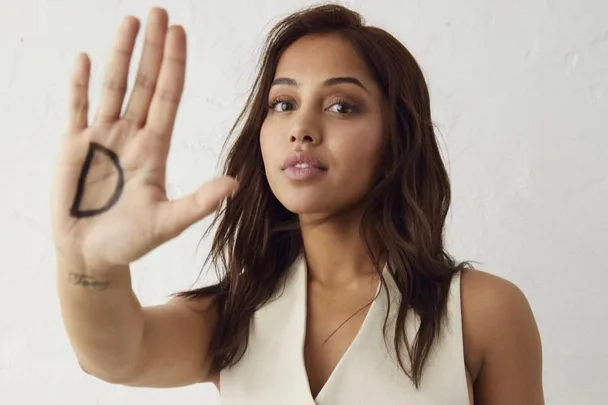 Woman holding up her hand with a "D" drawn on the palm, symbolizing one of the five D's of street harassment intervention.