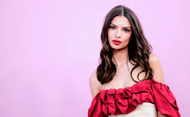 Person in a ruffled red dress against a pink background.